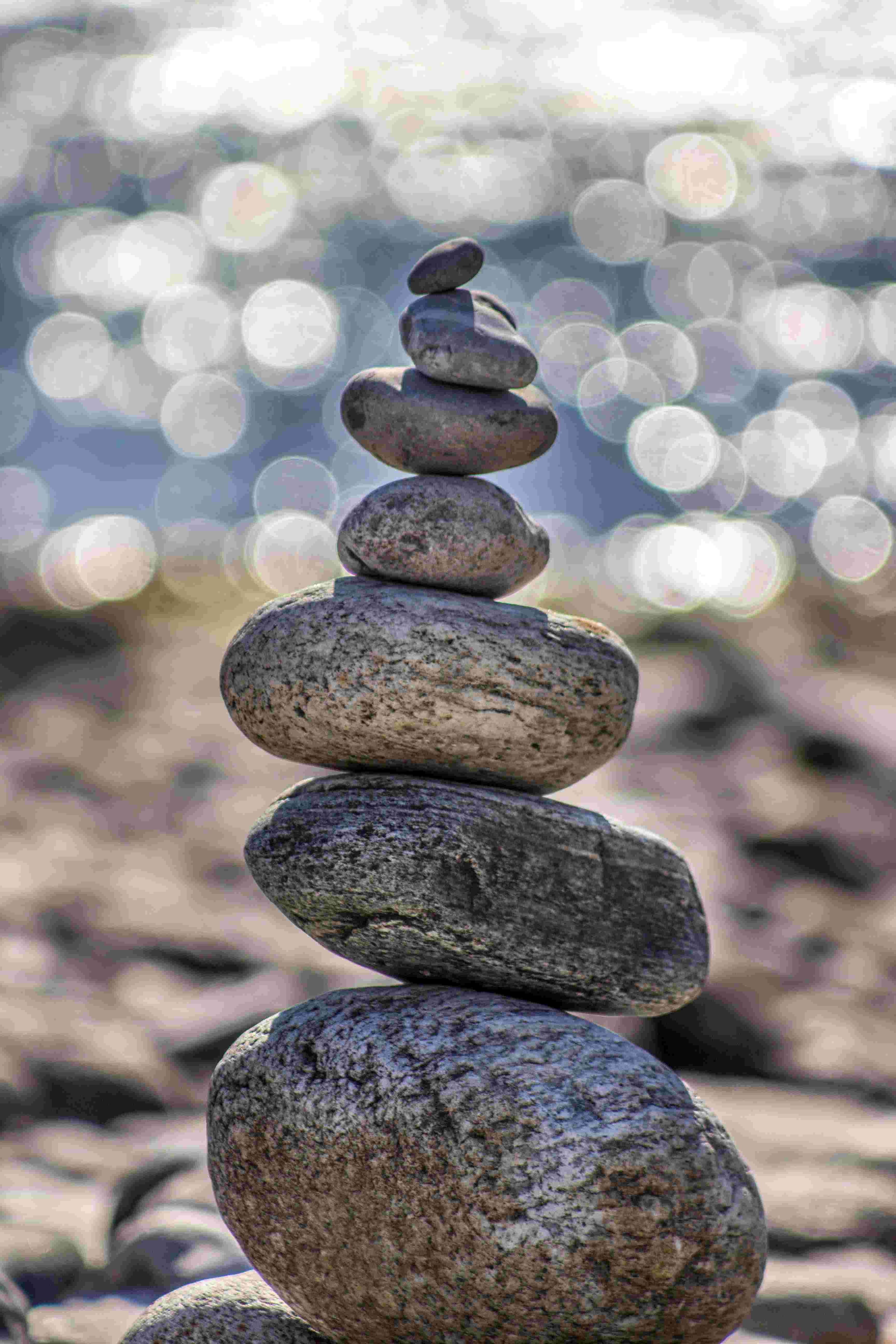 a vertical stack of rocks on the sand with the ocean in the background